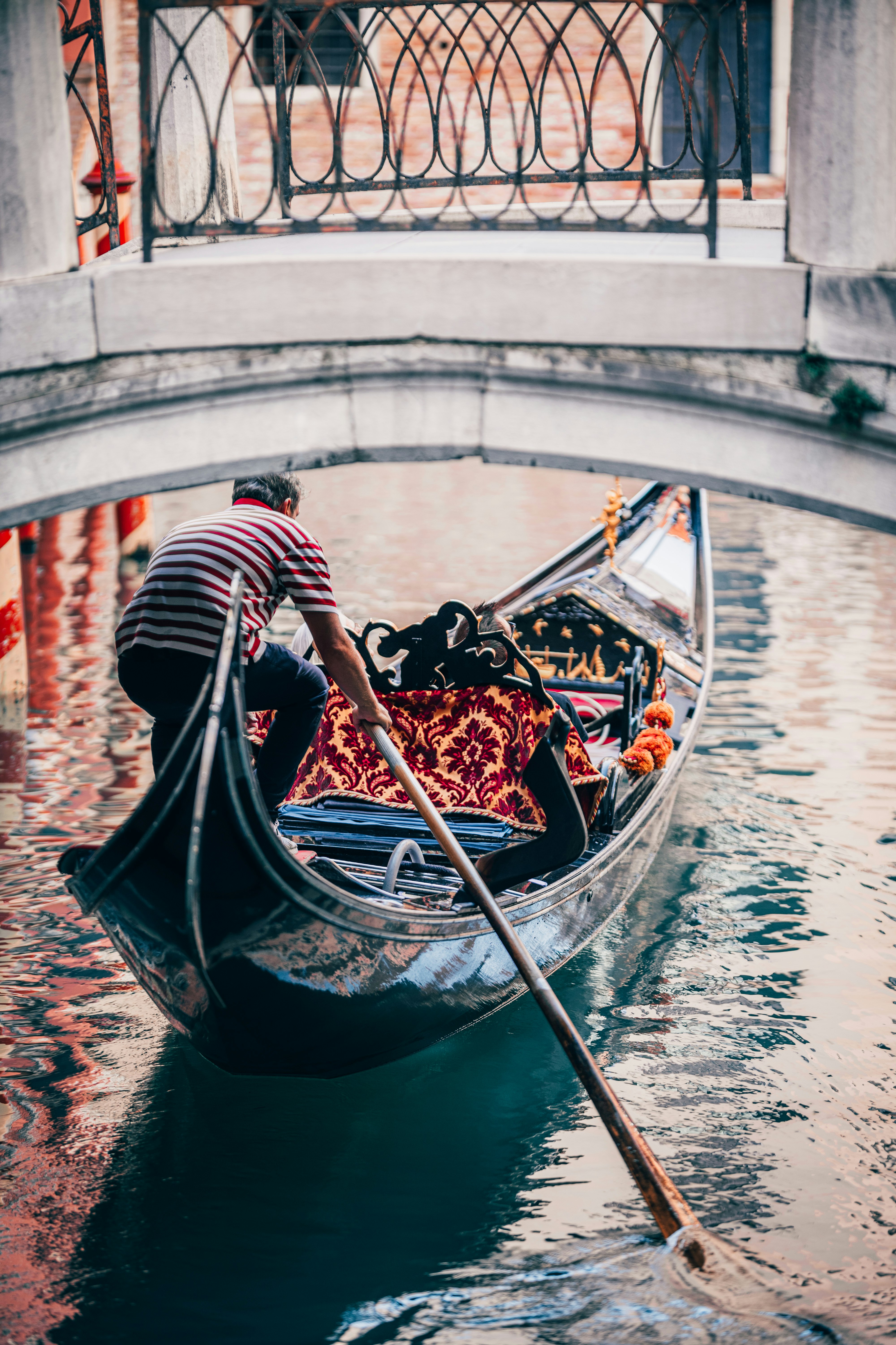 man in black and red striped shirt riding on black boat during daytime